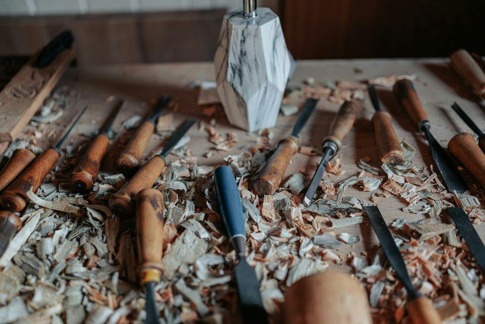 Wood carving chisels and a marble mallet laid out on a workbench