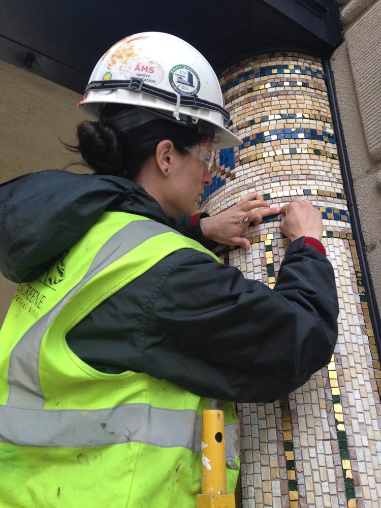 Conservator framing and resetting mosaic tesserae on a column