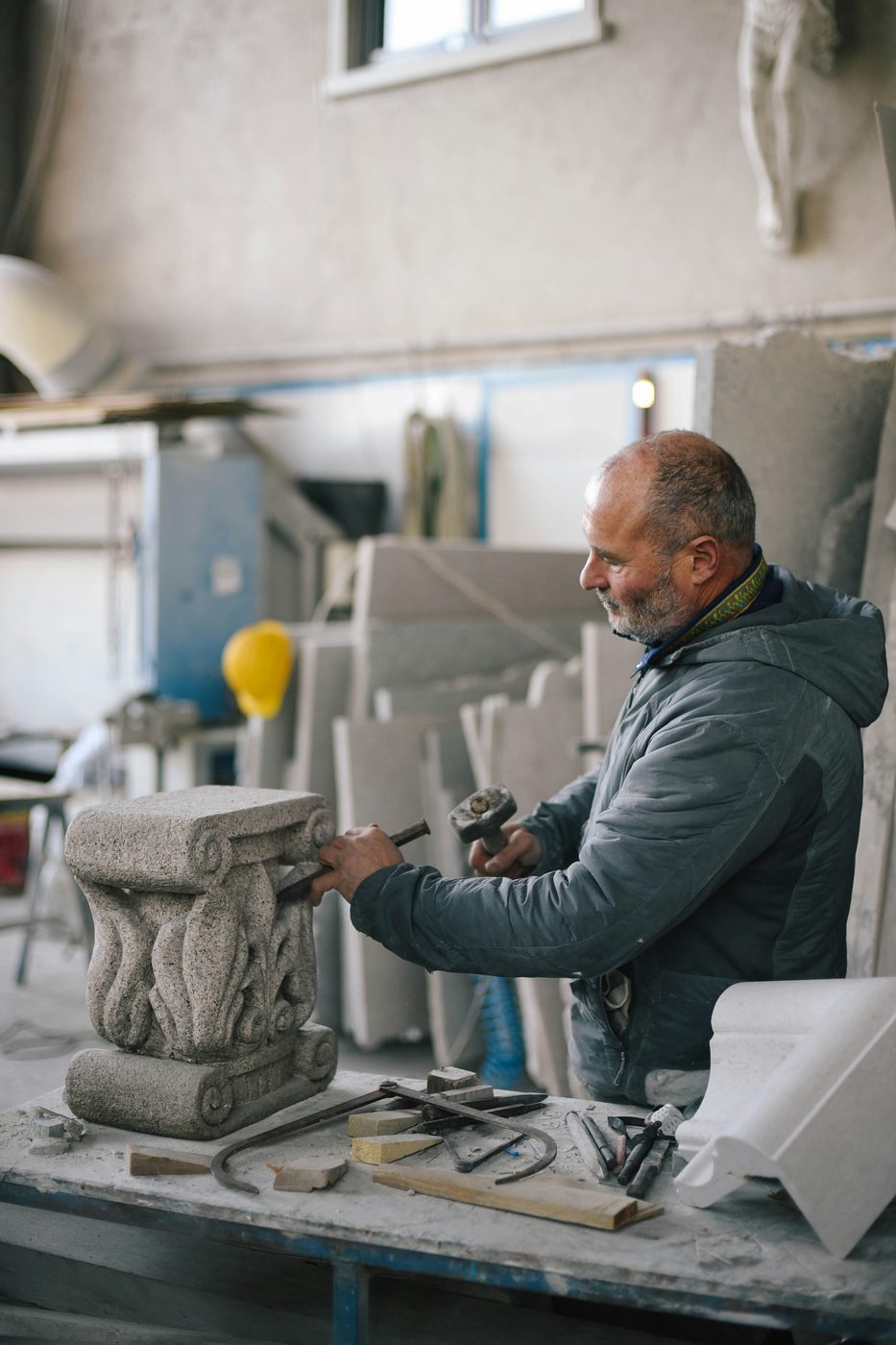 Stonemason carving a stylized capital by hand